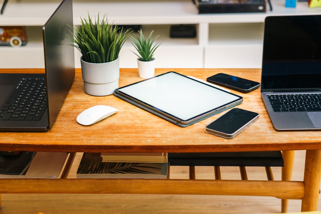 Devices like laptops, tablets, and phones are on a desk.